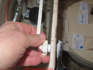 Unscrewing the lock nut that holds a toilet flush lever in place (C) Daniel Friedman at InspectApedia.com